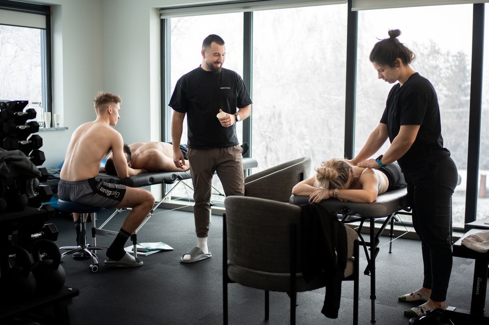 Sala szkoleniowa Move Therapy — uczestnicy kursu masażu tkanek głębokich pracują w parach na leżankach