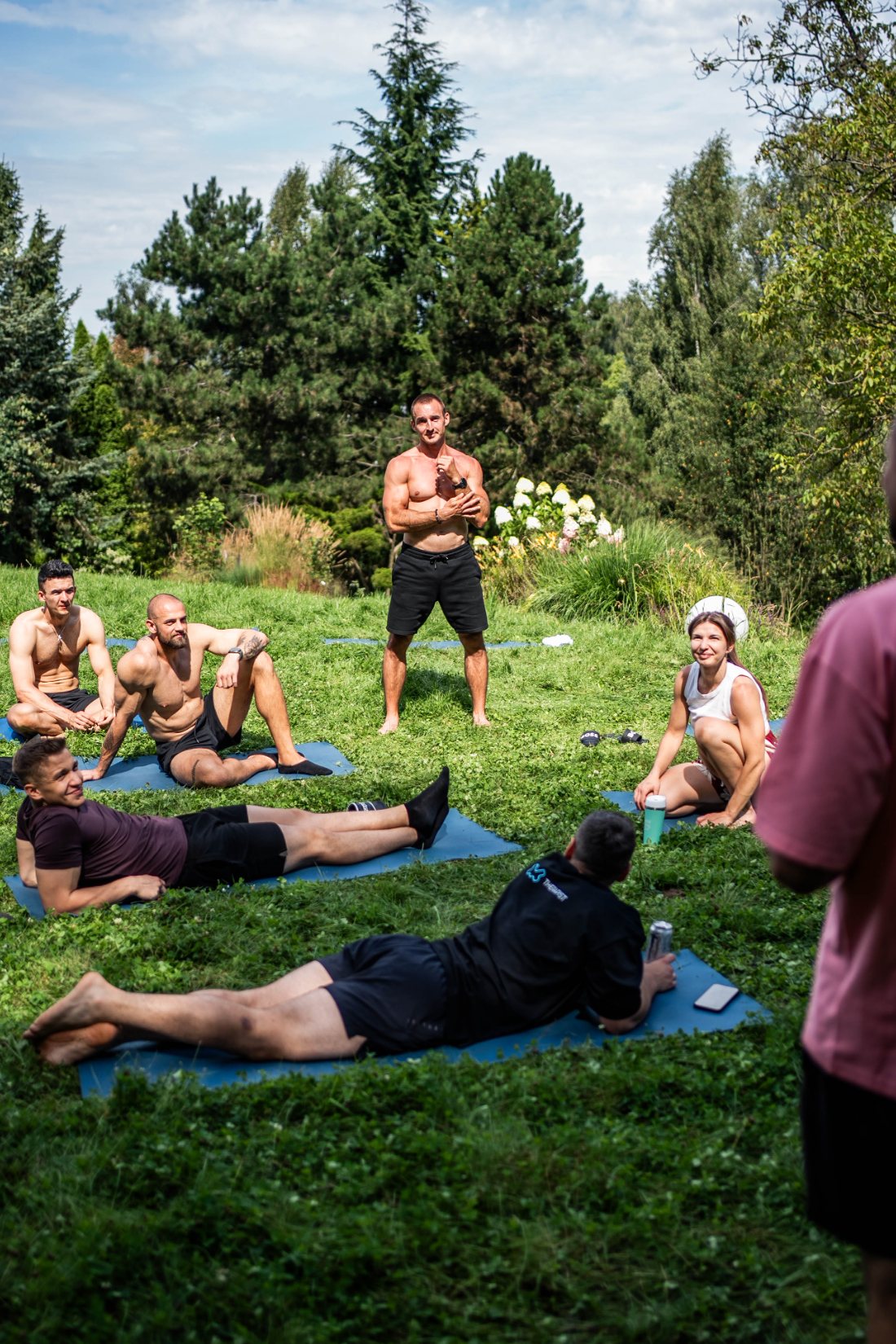 Uczestnicy Somatic Movement Camp podczas pracy somatycznej na łące, prowadzący omawia ćwiczenie